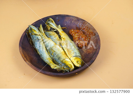 Fried milkfish with sambal, traditional Indonesian culinary dish, served on a wooden plate. Fried milkfish with sambal, traditional Indonesian culinary dish, served on a wooden plate. 132577900
