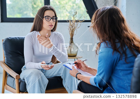 Sad teenage girl student talking with social psychologist, therapist, counselor Sad teenage girl student talking with social psychologist, therapist, counselor 132578898