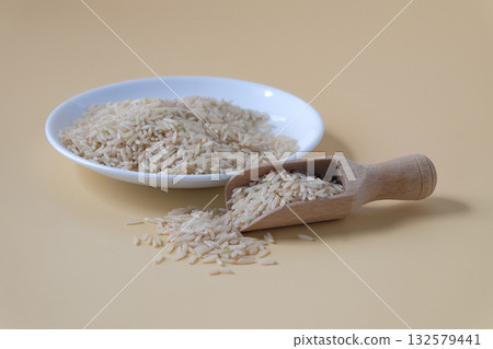 Raw Brown rice, uncooked and hulled in plate. 132579441