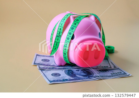 A Measuring tape for tying piggy bank with banknotes ,Business concept. A Measuring tape for tying piggy bank with banknotes ,Business concept. 132579447