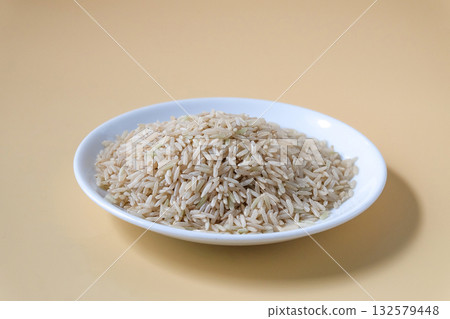 Raw Brown rice, uncooked and hulled in plate. 132579448