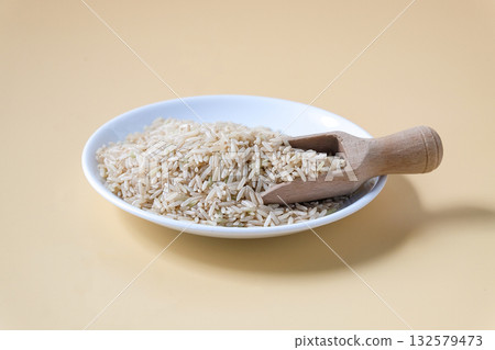 Raw Brown rice, uncooked and hulled in plate. 132579473