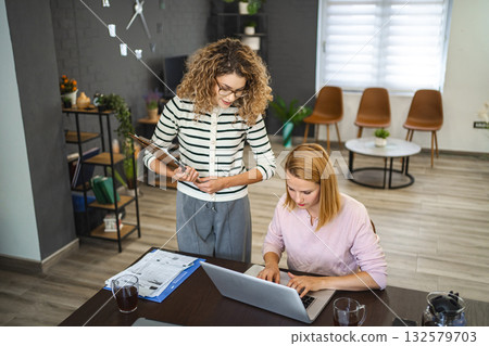 Two female colleagues working together on business report Two female colleagues working together on business report 132579703
