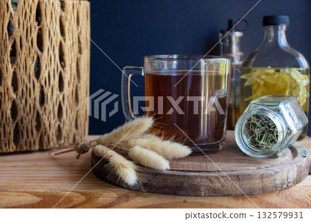 Hot herbal tea on a rustic wooden tray ,surrounded by dried rosemary and herbal jars 132579931