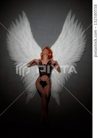 Sexy woman with big white angel wings leaning on the wall 132580558