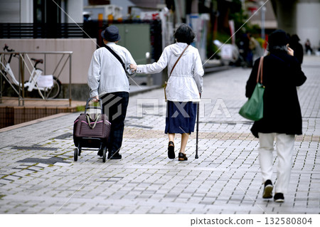 Yokohama cityscape in Japan: Aging society: Elderly man and woman with walking sticks (both wearing masks)... = October 28, Yokohama city Yokohama cityscape in Japan: Aging society: Elderly man and woman with walking sticks (both wearing masks)... = October 28, Yokohama city 132580804