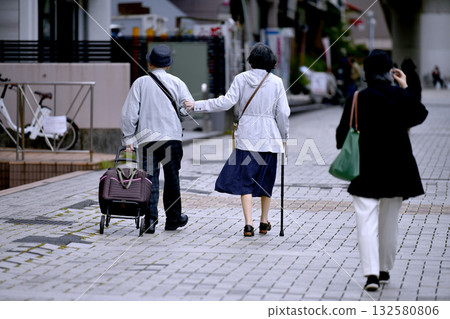 Yokohama cityscape in Japan: Aging society: Elderly man and woman with walking sticks (both wearing masks)... = October 28, Yokohama city Yokohama cityscape in Japan: Aging society: Elderly man and woman with walking sticks (both wearing masks)... = October 28, Yokohama city 132580806