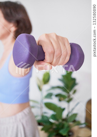 Female adult exercising with purple dumbbell at home. 132580890