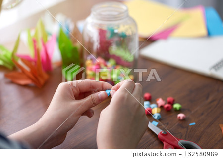 Woman's hand folding a star from colorful origami paper for a gift or decoration for the festival of happiness and hope. 132580989