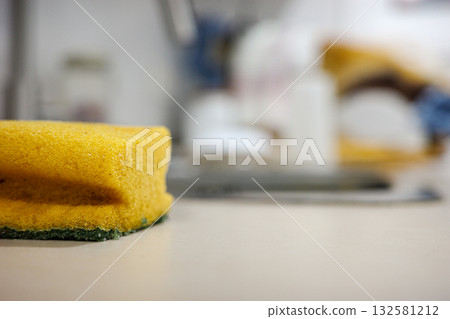 Yellow kitchen sponge on a countertop in soft focus background Yellow kitchen sponge on a countertop in soft focus background 132581212