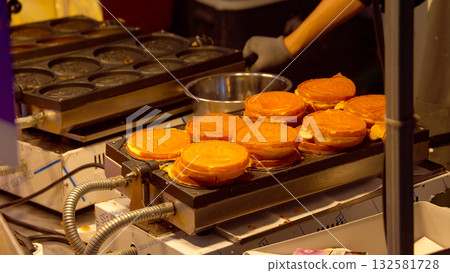 Seoul street food vendor preparing Korean waffles at night Seoul street food vendor preparing Korean waffles at night 132581728