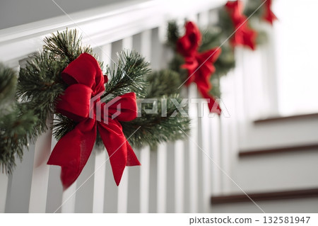 Christmas garland with red bows adorns a stair railing. 132581947