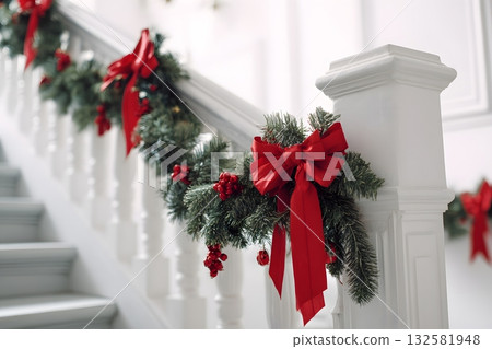 Christmas garland with red bows adorns a white staircase railing. 132581948