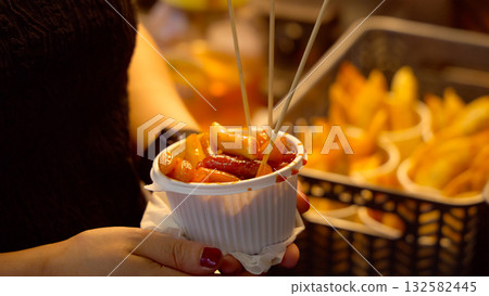 Person holding Korean street food tteokbokki and sausage 132582445