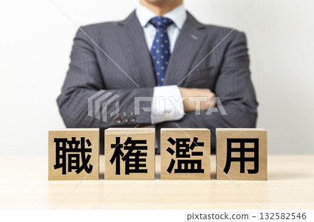 一位商人雙手交叉放在胸前,旁邊立著一塊寫著「濫用職權」的牌子。 一位商人雙手交叉放在胸前,旁邊立著一塊寫著「濫用職權」的牌子。 132582546