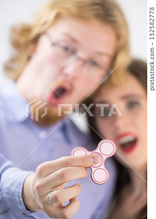 Couple playing with fidget spinner Couple playing with fidget spinner 132582778