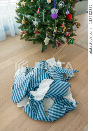 Christmas gift wrap waste on floor highlighting excessive paper use after holiday unwrapping. 132582822