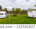 Two retro camper trailers parked on green grass near lake with wooden shelter, copy space 132582827