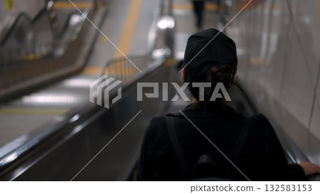 Woman riding escalator in Seoul subway station 132583153