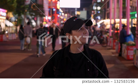 Woman exploring a bustling street in Seoul at night 132583156