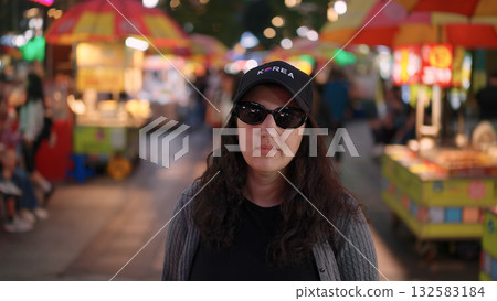 Woman wearing Korea hat enjoying Busan night market street food Woman wearing Korea hat enjoying Busan night market street food 132583184