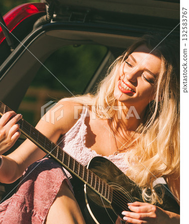 Girl with guitar on hatchback car Girl with guitar on hatchback car 132583767