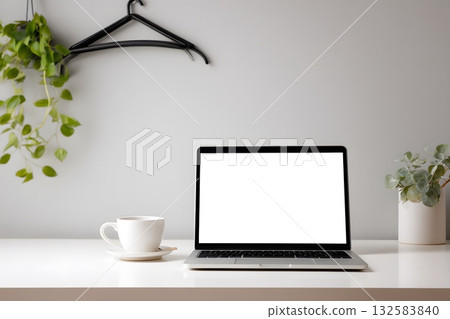 A laptop sits open on a desk with a plant and coffee. A laptop sits open on a desk with a plant and coffee. 132583840