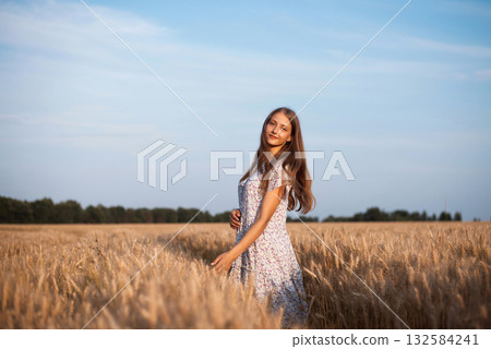 Portrait of a girl in ripe field of rye at sunset 132584241
