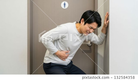 一名男子在廁所前痛苦地忍受著劇烈的胃痛。 一名男子在廁所前痛苦地忍受著劇烈的胃痛。 132584358