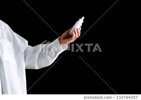 A white serum in the hand of a girl in a white shirt on a black background. A white serum in the hand of a girl in a white shirt on a black background. 132584387