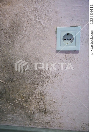 Close-up of mold and damp stains on a wall near an electrical socket, showing moisture damage and unhealthy indoor conditions. Suitable for home repair, maintenance, and moisture problem themes. Close-up of mold and damp stains on a wall near an electrical socket, showing moisture damage and unhealthy indoor conditions. Suitable for home repair, maintenance, and moisture problem themes. 132584411