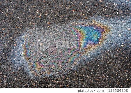 Oil spill on wet asphalt pavement showing multicolored rainbow sheen and pollution concept Oil spill on wet asphalt pavement showing multicolored rainbow sheen and pollution concept 132584598
