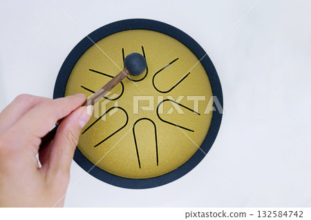 Hand Playing Tongue Drum with Mallet 132584742