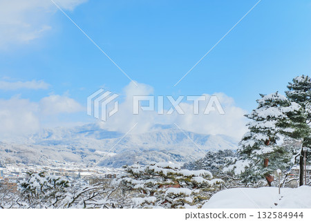 A view of the snow-covered cityscape from Kenrokuen Garden in Kanazawa and a distant view of Mt. Io shining against a clear winter sky A view of the snow-covered cityscape from Kenrokuen Garden in Kanazawa and a distant view of Mt. Io shining against a clear winter sky 132584944