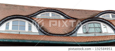 Old beautiful european german fachwerk building rooftop with eye shaped windows and chimney. Typical traditional ancient house roof architecture in Europe. Funny face-shaped pareidolia facade 132584951