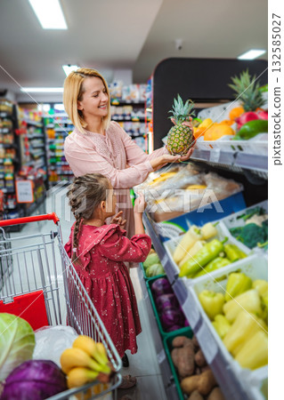 Mother and daughter shopping for fresh fruit in supermarket 132585027