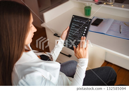 Woman checking daily tasks on digital checklist tablet Woman checking daily tasks on digital checklist tablet 132585094