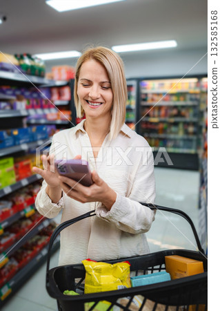 Woman smiling using smartphone shopping in grocery store Woman smiling using smartphone shopping in grocery store 132585168
