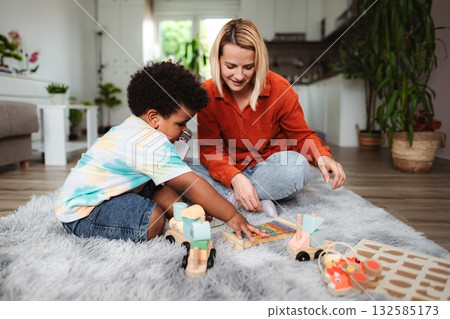Mother and son playing with wooden toys on rug at home Mother and son playing with wooden toys on rug at home 132585173