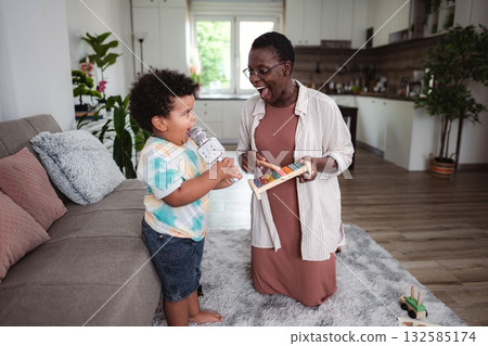 Grandmother and grandson playing music together at home 132585174