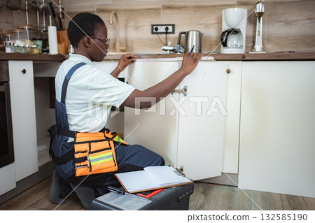 Handyman taking measurements of kitchen cabinets using tape measure Handyman taking measurements of kitchen cabinets using tape measure 132585190
