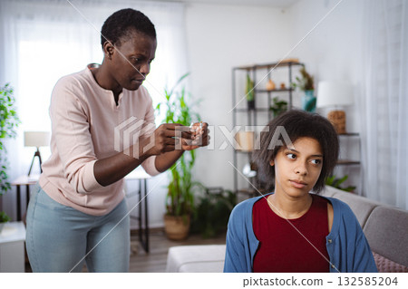 Mother breaking cigarettes and showing to her teenage daughter at home Mother breaking cigarettes and showing to her teenage daughter at home 132585204