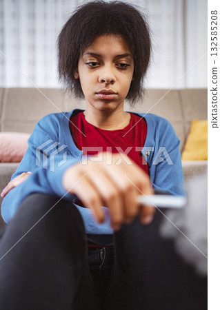 Young woman smoking a cigarette at home looking down Young woman smoking a cigarette at home looking down 132585208