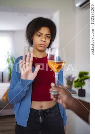Young woman refusing a glass of wine offered by someone 132585209