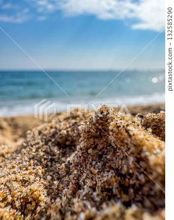 Macro View of Sand Grains on Beach with Sea in Background 132585290