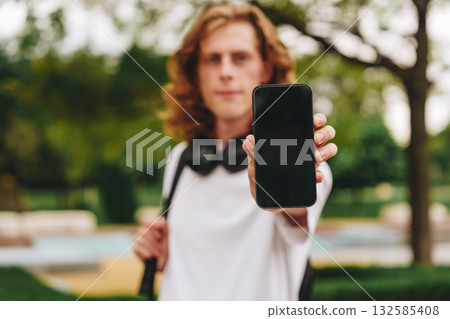 Young person displaying a smartphone in a park setting during the afternoon Young person displaying a smartphone in a park setting during the afternoon 132585408