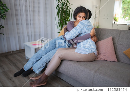 Mother and daughter are hugging on the sofa in the living room Mother and daughter are hugging on the sofa in the living room 132585454