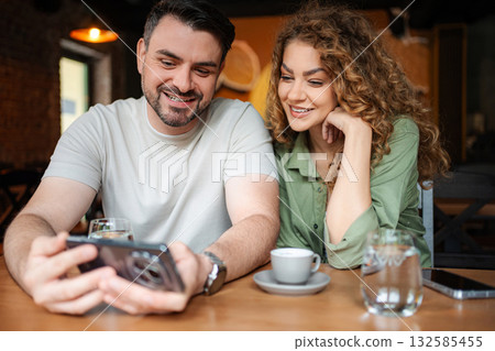 Couple enjoying coffee and looking at smartphone in cafe 132585455