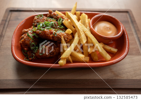 Crispy chicken wings served with golden fries and spicy sauce 132585473