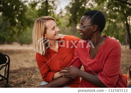 Two Smiling Women Embracing and Sharing a Moment in the Park 132585512